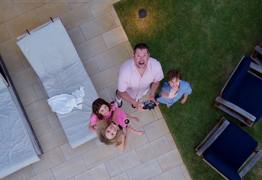 Aerial family portrait of Leah, her husband, and their two children looking up from a backyard patio in Tucson, Arizona.